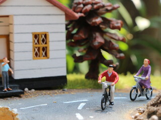 a close up of a miniature figure of a cyclist greeting other people. social photo concept.