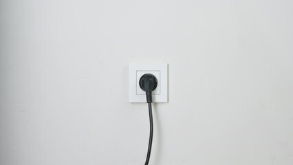 Male hand plugging and unplugging plug into white wall socket. Close-up power socket, caucasian man, charger cable