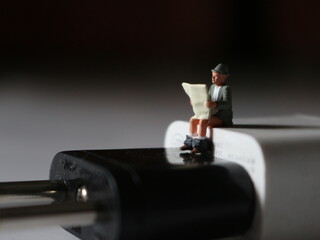 a close up of a miniature figure of a person reading above a cell phone charger.