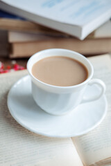 Fototapeta na wymiar Coffee in a white cup stands on a book, close-up