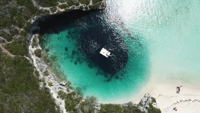 aerial view of dean's blue hole. drone sinks slowly and you can see the divers preparing