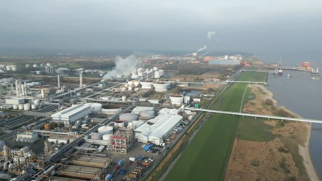Smoke and steam rising of an industrial facility on a river, CO2 emissions, air pollution, exhaust gases, aerial