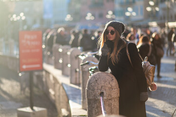Young stylish blondie woman enjoying the Italian antic Roman Arena di Verona in trendy knitted hat,...