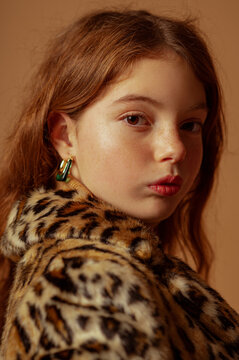Fashionable confident redhead freckled girl wearing trendy faux fur coat with leopard print. Close up studio fashion portrait
