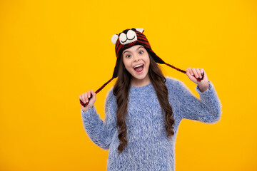 Amazed teenager. Modern teenage girl 12, 13, 14 year old wearing sweater and knitted hat on isolated yellow background. Excited teen girl.