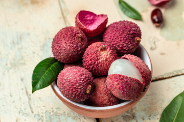 Fresh lychee and peeled showing the red skin with cut in half and leaves, Food background. Close up