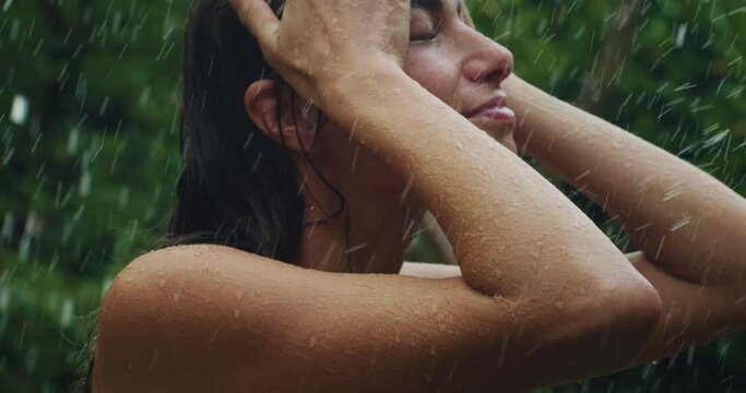 Portrait of Beautiful Happy Woman Sensually Standing Under the Rain Surrounded By Nature and Trees. Happy Female Adult Enjoying the Water Drops and Reaching Inner Peace and Wellness 