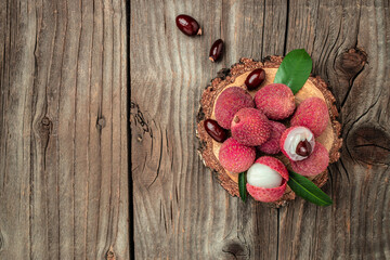 fresh ripe lychee fruit and peeled lychee with green leaves on a wooden background. banner, menu, recipe place for text, top view