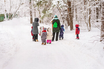Winter. Cute preschoolers group of kindergarten and 2 kindergarten teachers on walk in forest. Active outdoor lifestyle