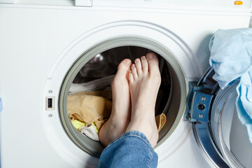 Woman feet in the open hatch of a washing machine....