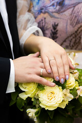 Obraz na płótnie Canvas Hands of bride and groom with new wedding silver rings on wedding bouquet 