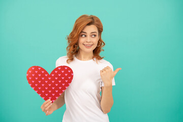 positive young woman with red heart on blue background. thumb up