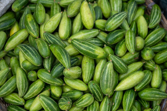 Pictures of fresh pointed gourd sold in a market.
