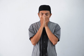 young asian muslim man cover face with hands praying concept, wearing grey koko clothes isolated on white background