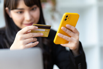 Attractive Asian businesswoman holding credit card and using smartphone. Online shopping concept.