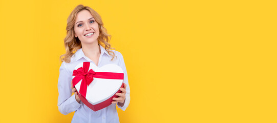 glad woman hold present heart box on yellow background. Woman isolated face portrait, banner with mock up copy space.