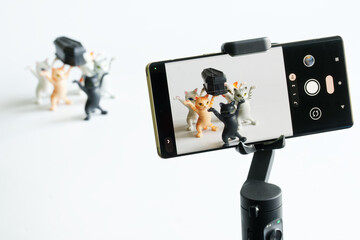 Modern smartphone on a gimbal selfie stick for photo-video filming the funeral procession of toy...