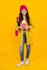 Back to school. Teenager schoolgirl in autumn wear hold toy. School children with favorite toys on isolated yellow studio background. Happy teenager, positive and smiling emotions of teen girl.