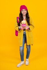 Back to school. Teenager schoolgirl in autumn wear hold toy. School children with favorite toys on isolated yellow studio background. Happy teenager, positive and smiling emotions of teen girl.