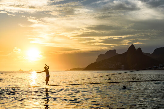 Slacklining In Arpoador Beach During The Sunset, Rio De Janeiro, Brazil