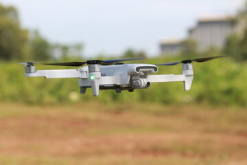 a photo of a drone flying with a blurry propeller against a green open space background. technology photo concept.