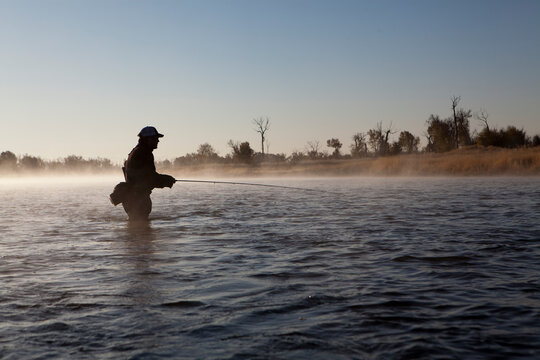 A man fishing in the early morning mist of the Green river.