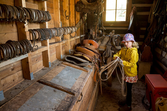 Young girl coiling rope in tack room while getting ready for horseback ride