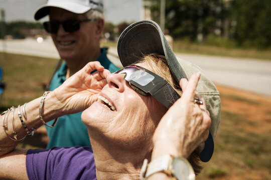 Senior woman watching solar eclipse through glasses, Anderson, South Carolina, USA