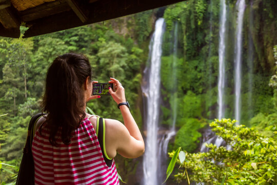 Woman taking waterfall pictures with her smart phone