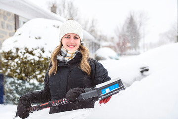 Woman cleans his car after a snowfall on a sunny, frosty day