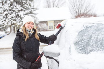 Woman cleans his car after a snowfall on a sunny, frosty day