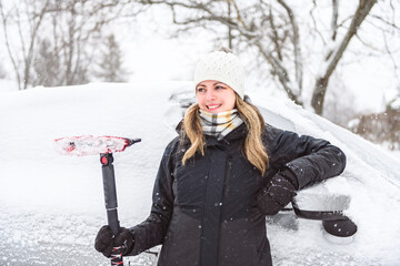 Woman cleans his car after a snowfall on a sunny, frosty day