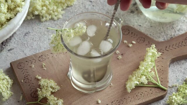 Stirring homemade drink made from elder flower syrup in a glass