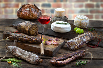 Local wild pork delicatessen, and corsican cheese, on an old brick wall background - obrazy, fototapety, plakaty