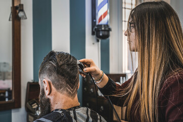 Hipster man at barbershop salon getting beard and hair cut - Hairdresser woman using hair clipper...