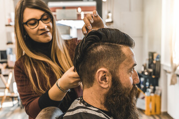 Hipster man at barbershop salon getting beard and hair cut - Hairdresser woman using hair scissors and comb for to modern gentleman cut - Barber shop concept