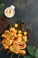 Christmas or New Year appetizer. Christmas tree shape puff pastry buns with cheese and ham. Group of Christmas tree shapes on wooden board. Festive idea for Christmas or New Year dinner. Top view.
