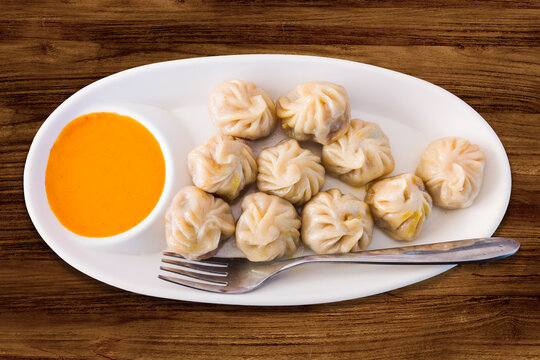 Steam-cooked momos with sauce, Nepalese Traditional Dish Momo. Authentic Cuisine in Nepal momo over a rustic wooden background.