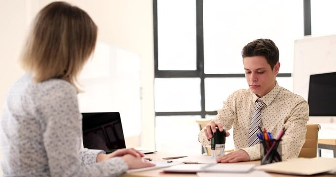 Manager putting seal on document in front of client in office 4k movie slow motion 