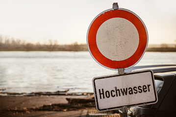 Schild vor Straßensperrung an Fluß mit Hochwasser