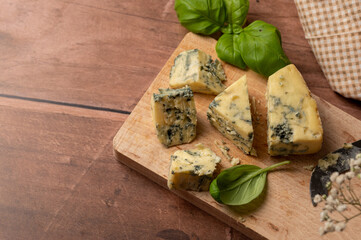 Blue cheese slices, wooden rustic background, copy space