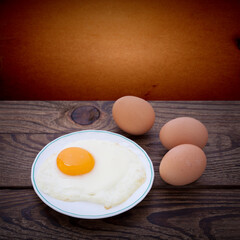 Plate with fried eggs on wooden background
