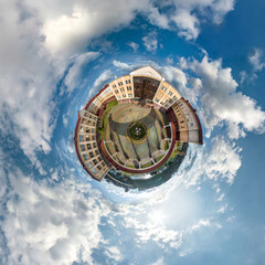 tiny planet in sky with clouds overlooking old town, urban development, historic buildings and...