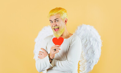 Bearded man in angelic wings with red paper heart. Valentines day card. Valentine cupid angel.