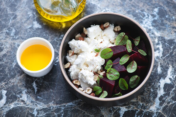 Bowl with beetroot and feta cheese salad, horizontal shot on a black marble background, elevated view