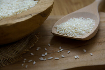 White dry rice on a wooden vintage spoon and bowl in close-up