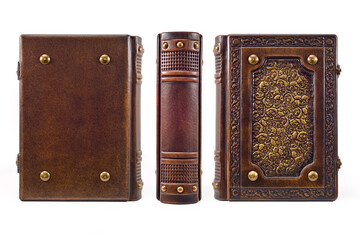 Brown aged leather book cover, rich decorated with patterned skulls, captured from three sides.