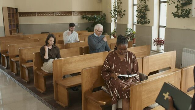 High angle shot of Catholic priest and parishioners crossing themselves at Sunday service in church