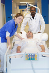 Obraz premium group of doctors carrying man patient on hospital gurney