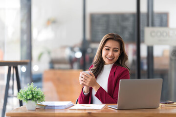 Attractive young asian woman using laptop computer while standing in a office.